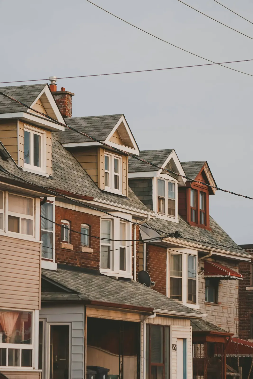 Row of brick houses with dormers under a cloudy sky